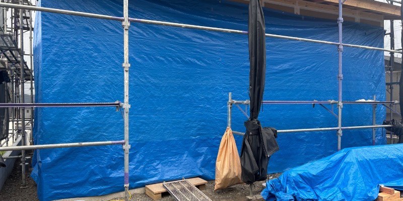 ホウ酸処理後の木材をシートで雨養生している現場の様子